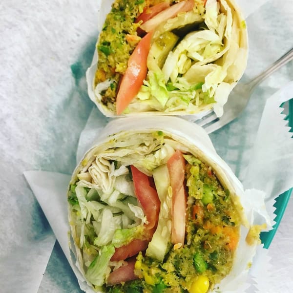 Two Mr. Submarine & Salads wraps, filled with green falafel, lettuce, tomatoes, and pickles.